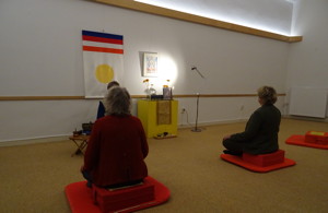 Meditators op de rug gezien met schrijn en Shambhala vlag op de achtergrond